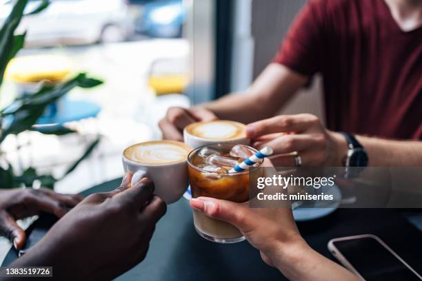 unrecognizable male and female friends toasting with coffees in a coffee shop - hand pastry stock pictures, royalty-free photos & images