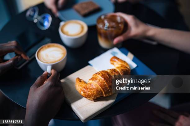 unrecognizable male and female friends having coffee and breakfast in a coffee shop - coffee croissant stock pictures, royalty-free photos & images