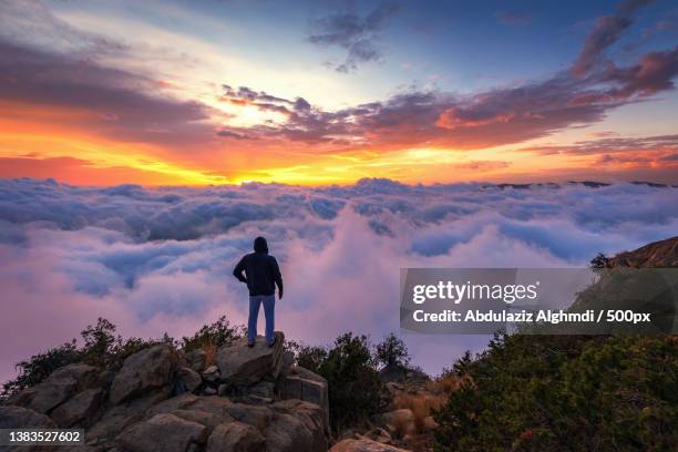 contemplate the clouds,man standing on mountain against sky during sunset,saudi arabia - saudi arabia landscape stock pictures, royalty-free photos & images