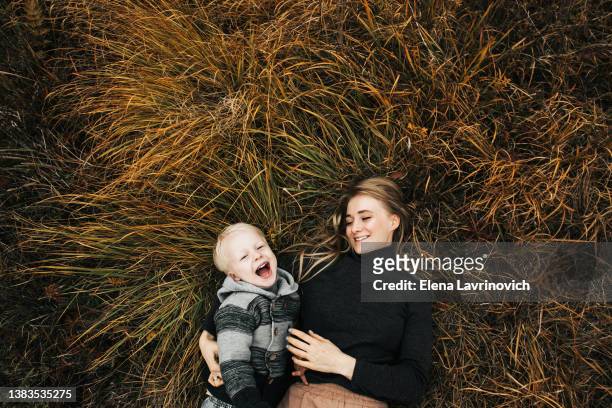 mom and son lie on the grass and laugh. view from above. happy mother's day. autumn photo - moments daily life from above photos et images de collection