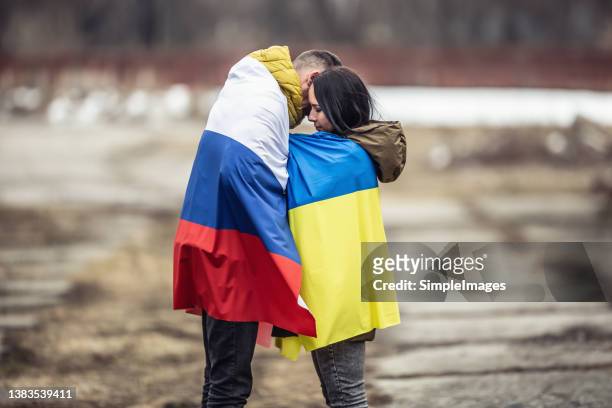 symbol of peace between russia and ukraine as young couple hugs dressed in their national flags. - ukraine war 個照片及圖片檔