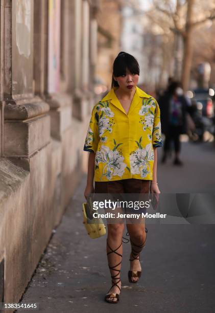 Susie Lau wears a yellow Valentino flower print blouse, a brown Valentino short, black sandals and a yellow Valentino handbag, seen outside...