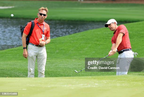 Rory McIlroy of Northern Ireland plays a shot watched by Brad Faxon of the United States during a practice round prior to THE PLAYERS Championship at...