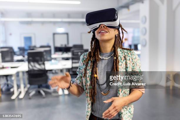 woman testing new metaverse using virtual reality glasses in office - top prospects game stock-fotos und bilder