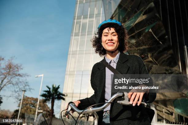 business woman smiling while riding her bike on her way to work office in the financial district. - woman cycling stock pictures, royalty-free photos & images