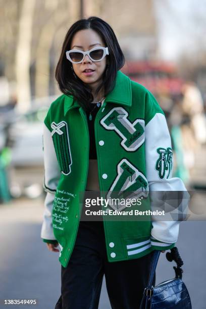 Guest wears oversized rhinestones earrings, white sunglasses, a black cropped t-shirt, a green with white sleeves and yoke pattern oversized teddy...