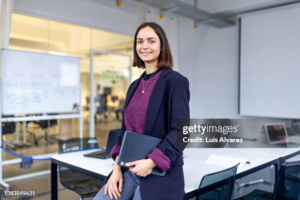 portrait of a smiling businesswoman standing in office meeting room - purple photos et images de collection