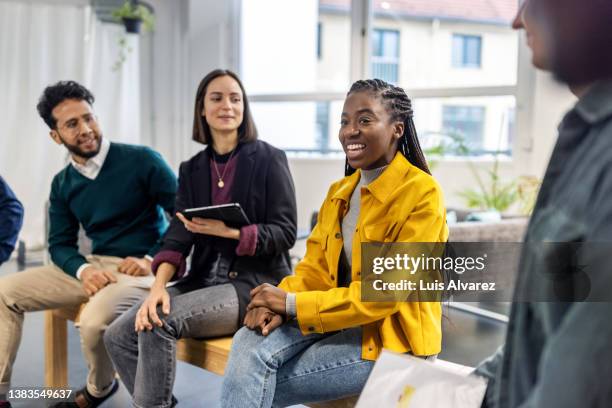 group of colleagues having a brainstorming session at startup office - multi coloured shirt stock-fotos und bilder