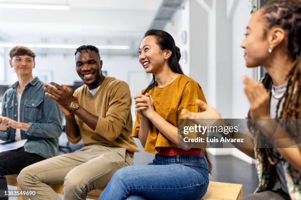 group of business people sitting in a circle clapping hands in meeting - asian working foto e immagini stock