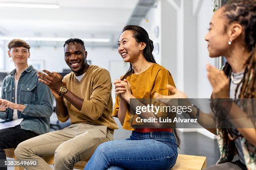 Group of business people sitting in a circle clapping hands in meeting Group of business people sitting in a circle clapping hands in meeting