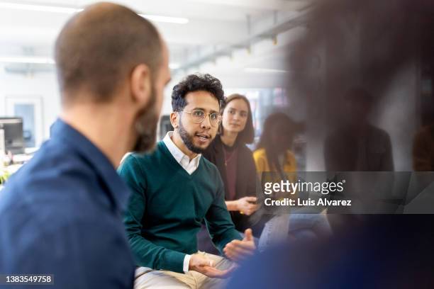 young middle eastern man talking with colleagues in meeting - eastern europe stockfoto's en -beelden