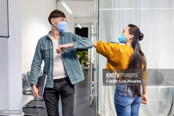 office workers greeting each other with elbow bump at work - pandemic illness stock-fotos und bilder