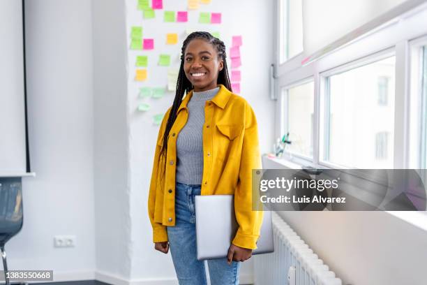 portrait of a smiling young woman working at startup company - porträt junge frau blick in kamera stock-fotos und bilder