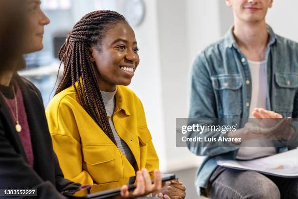 young woman sharing her ideas during team building session - yellow shirt stock pictures, royalty-free photos & images