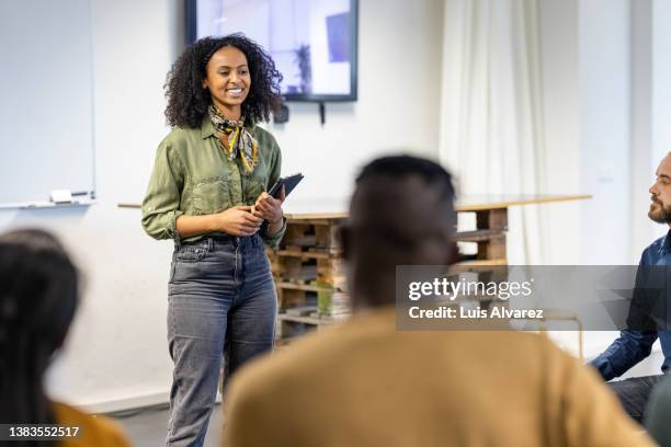 young businesswoman addressing group of people in meeting - 20 to 35 year old in class stock pictures, royalty-free photos & images