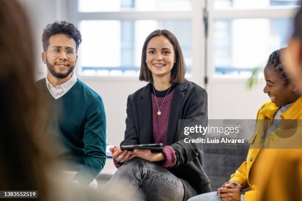 young woman holding digital tablet discussing work with team in office - staff meeting stock pictures, royalty-free photos & images