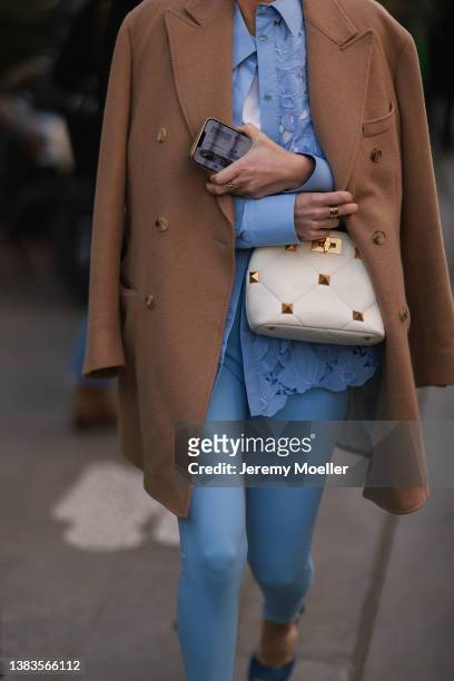 Fashion Week Guest is wearing a babyblue blouse, babyblue leggings, a brown whool coat, Iphone and a white Valentino bag outside Valentino during...