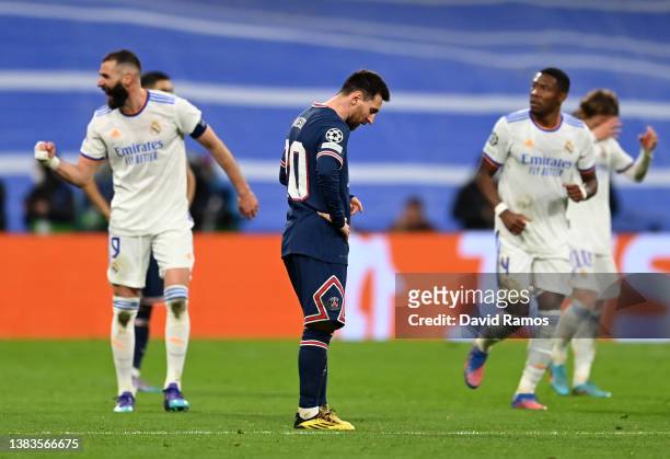 Lionel Messi of Paris Saint-Germain looks dejected after conceding their side's second goal while goal scorer Karim Benzema of Real Madrid celebrates...