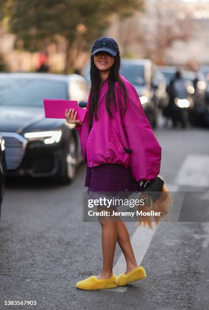 Fashion Week Guest is seen wearing a cap, pink jacket, a purple dress, yellow fluffy shoes outside Valentino during Paris Fashion Week - Womenswear...