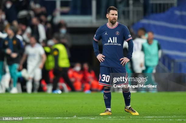 Lionel Messi of Paris Saint-Germain cuts a dejected figure as Karim Benzema of Real Madrid celebrates their sides third goal during the UEFA...