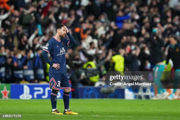 Lionel Messi of Paris Saint-Germain cuts a dejected figure as Karim Benzema of Real Madrid celebrates their sides third goal during the UEFA...