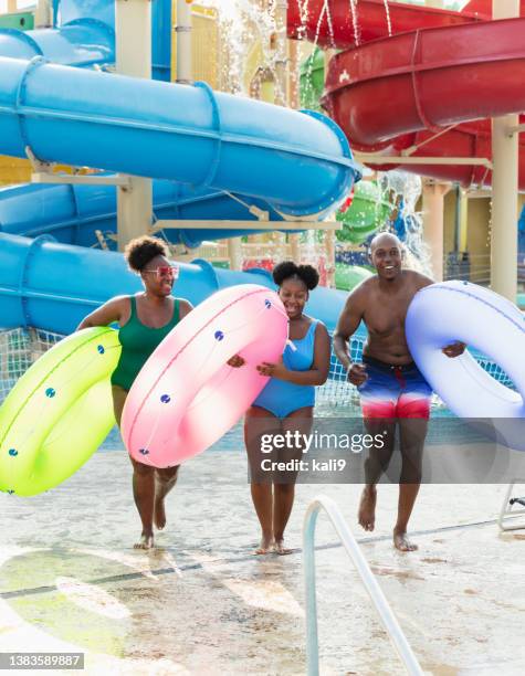 family at waterpark carry inflatable rings to lazy river - waterpark stock pictures, royalty-free photos & images