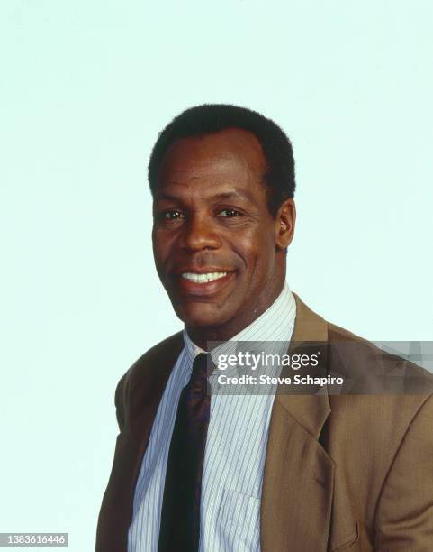 Portrait of American actor Danny Glover, in a tie and blazer, as he poses against a white background, Los Angeles, California, 1983.