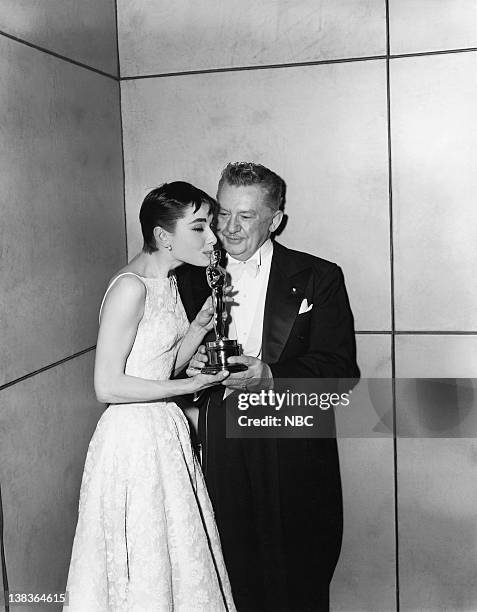 Pictured: Actress Audrey Hepburn, wearing a Givenchy gown, kisses her "Best Actress in a Leading Role" award for "Roman Holiday" and Danish actor,...