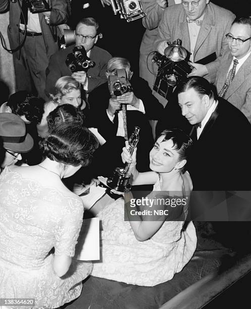 Pictured: Audrey Hepburn, wearing a Givenchy gown, surrounded by journalists after winning her Best Actress Oscar at the ceremony in New York City.