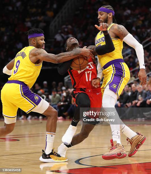 Dennis Schroder of the Houston Rockets drives between Kent Bazemore of the Los Angeles Lakers and Carmelo Anthony during the second quarter at Toyota...