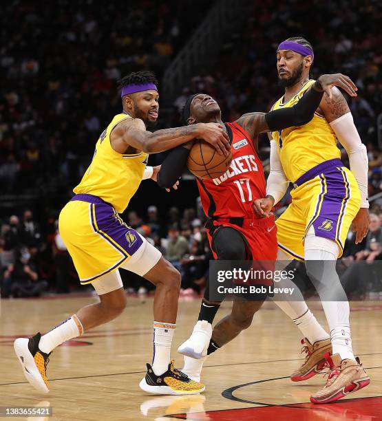 Dennis Schroder of the Houston Rockets drives between Kent Bazemore of the Los Angeles Lakers and Carmelo Anthony during the second quarter at Toyota...