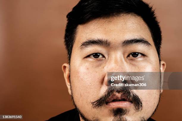 close up crop facial expression portrait asian young adult with beard  and pastel background - bearded iris stockfoto's en -beelden