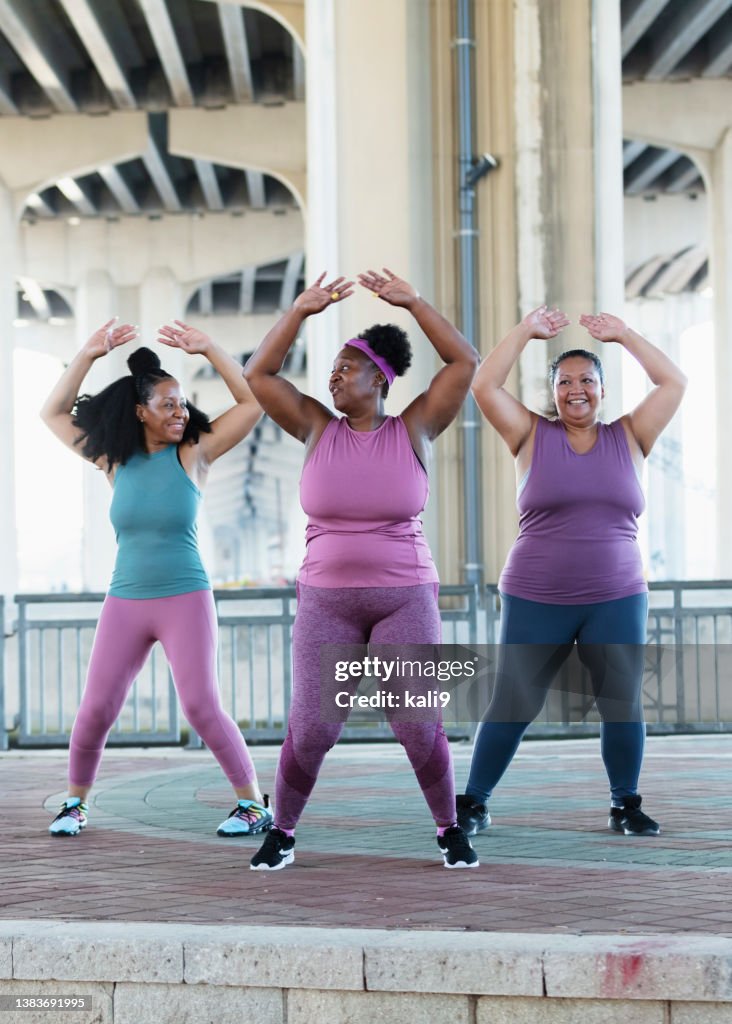 Three multiracial women doing jumping jacks
