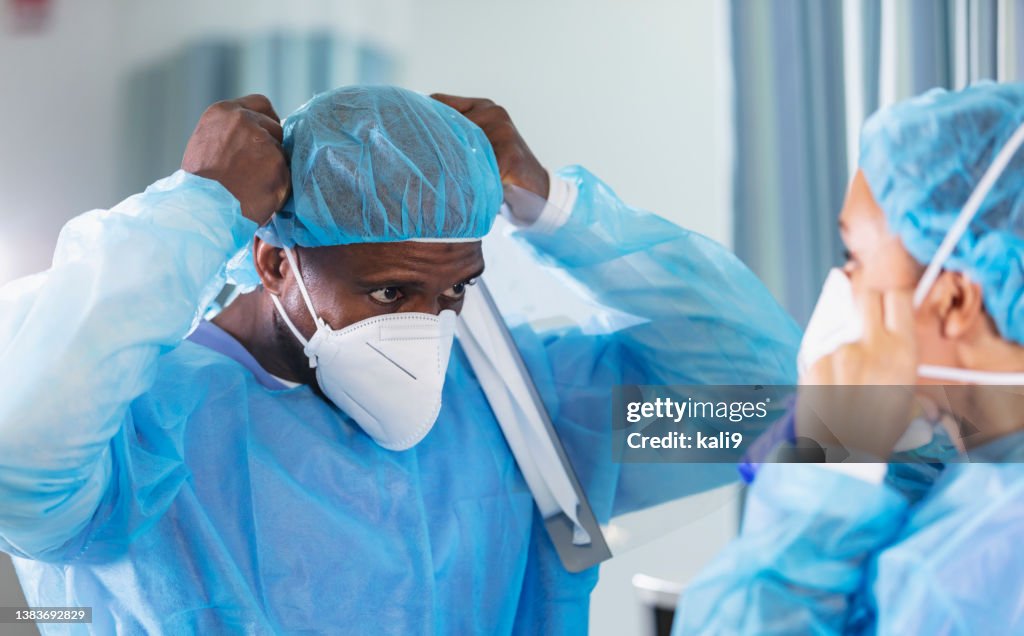 Dos trabajadores de la salud se ponen eppes y máscaras faciales N95