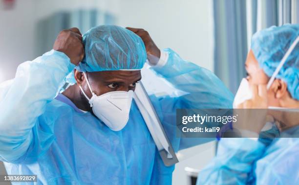 dos trabajadores de la salud se ponen eppes y máscaras faciales n95 - mascarilla n95 fotografías e imágenes de stock