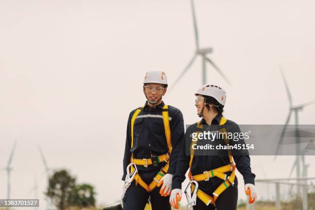 Engineer wearing  personal safety equipment PPE for safety process operation at Wind turbines or windmills farm in the rural for electric power production. Concept of Sustainable energy Renewable energy and clean energy concept. Engineer safety concept.