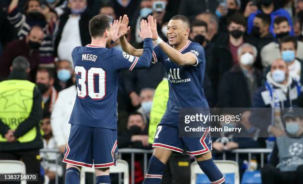 Kylian Mbappe of PSG celebrates his goal with Lionel Messi during the UEFA Champions League Round Of Sixteen Leg Two match between Real Madrid and...