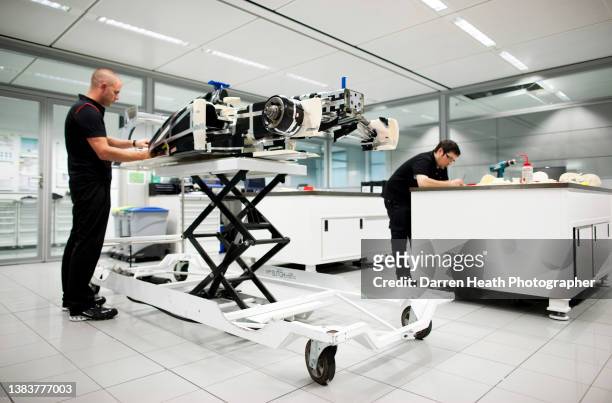 McLaren Formula One racing team engineers working in the team's race team research area on a wind tunnel model of a McLaren MP4-26 racing car while...