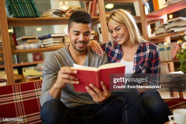 multi-ethnischen jungstudentin paar genießen buch lesen in der bibliothek - love books stock-fotos und bilder