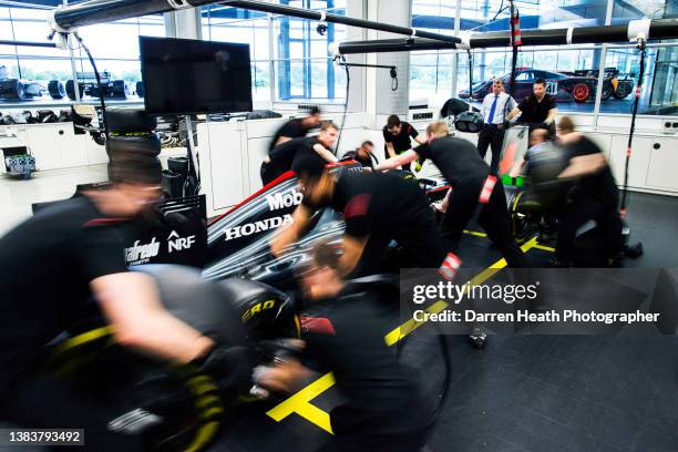 McLaren Formula One mechanics and their team manager undertaking a practice pit stop with a McLaren MP4-30 Formula One racing car in the McLaren...