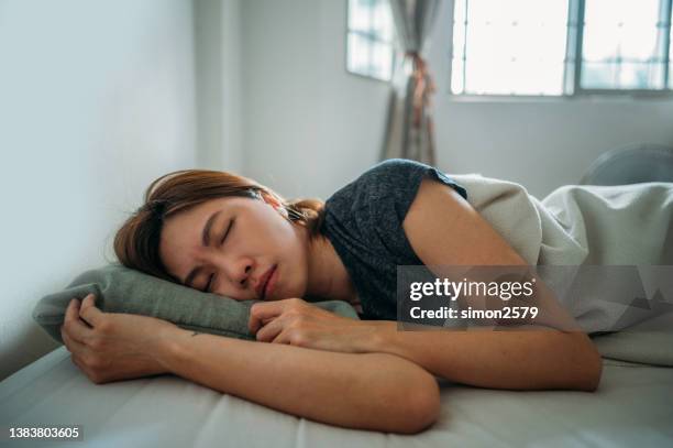 an asian woman sleeping under blanket at bedroom - sofa bed stock pictures, royalty-free photos & images
