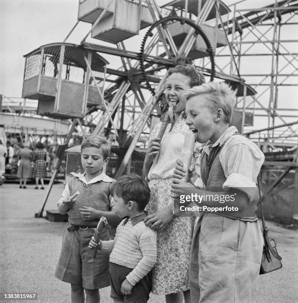 June, John, Tony and Roderick Arnold, evacuee children from a London family, enjoy eating sticks of rock on a visit to Blackpool Pleasure Beach...