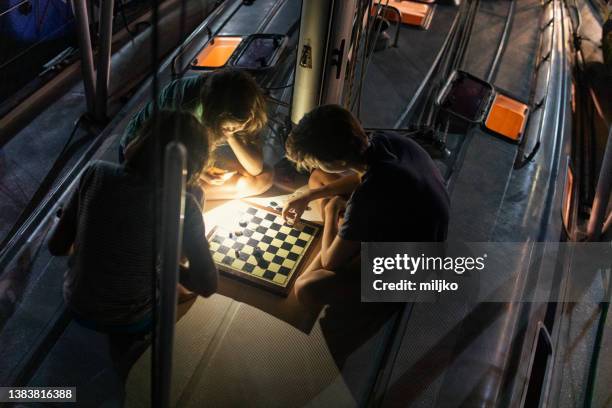 children playing board strategic game on yacht at night - sailing ship night stock pictures, royalty-free photos & images