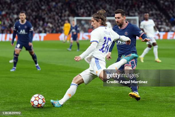 Luka Modric of Real Madrid is challenged by Lionel Messi of Paris Saint-Germain during the UEFA Champions League Round Of Sixteen Leg Two match...