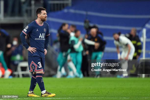 Lionel Messi of Paris Saint-Germain cuts a dejected figure as Karim Benzema of Real Madrid celebrates their sides third goal during the UEFA...