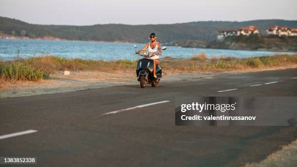 woman wearing motorcycle helmet and traveling on motorcycle in sea road - constituency stock pictures, royalty-free photos & images