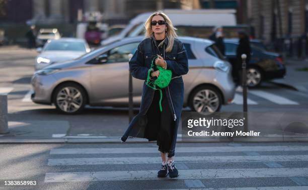 Fashion Week Guest wearing a blue jeans coat, a black midi dress, a green balenciaga leather bag outside Sacai during Paris Fashion Week on March 07,...