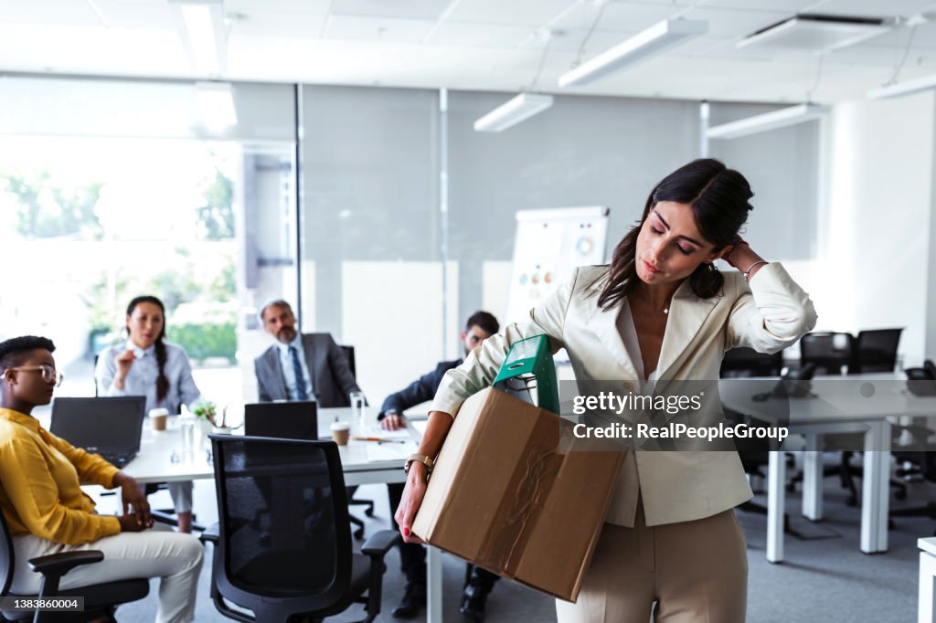 Mid adult businesswoman with cardboard box being fired