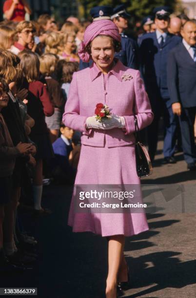 British Royal Queen Elizabeth ll, wearing a lilac suit with a checked collar and matching turban-style hat, during a walkabout in Wellington, New...