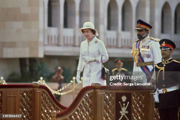 British Royal Queen Elizabeth ll, wearing a white coat and a white safari-style hat, alongside Sultan of Oman Qaboos bin Said at welcoming ceremony...